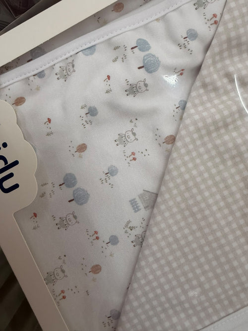 Detalle del arrullo reversible Babidu Granja beige con estampado infantil y cuadros
