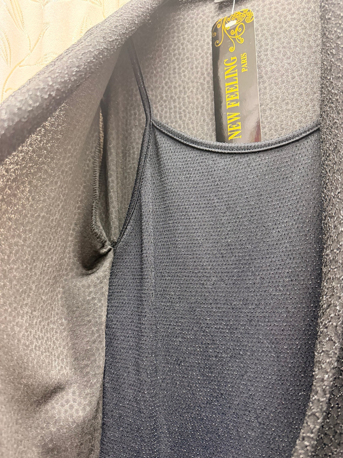 Detalle de tejido brillante de chaqueta negra cruzada de mujer