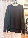 Jersey de mujer negro oversize con bolsillo delantero y bajo asimétrico