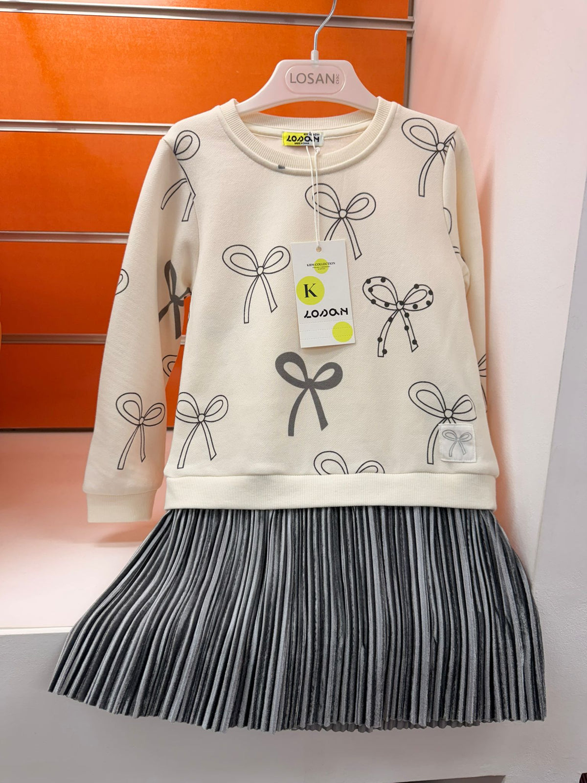 Vestido niña Losan crudo con estampado de lazos y falda plisada gris, talla 4 años